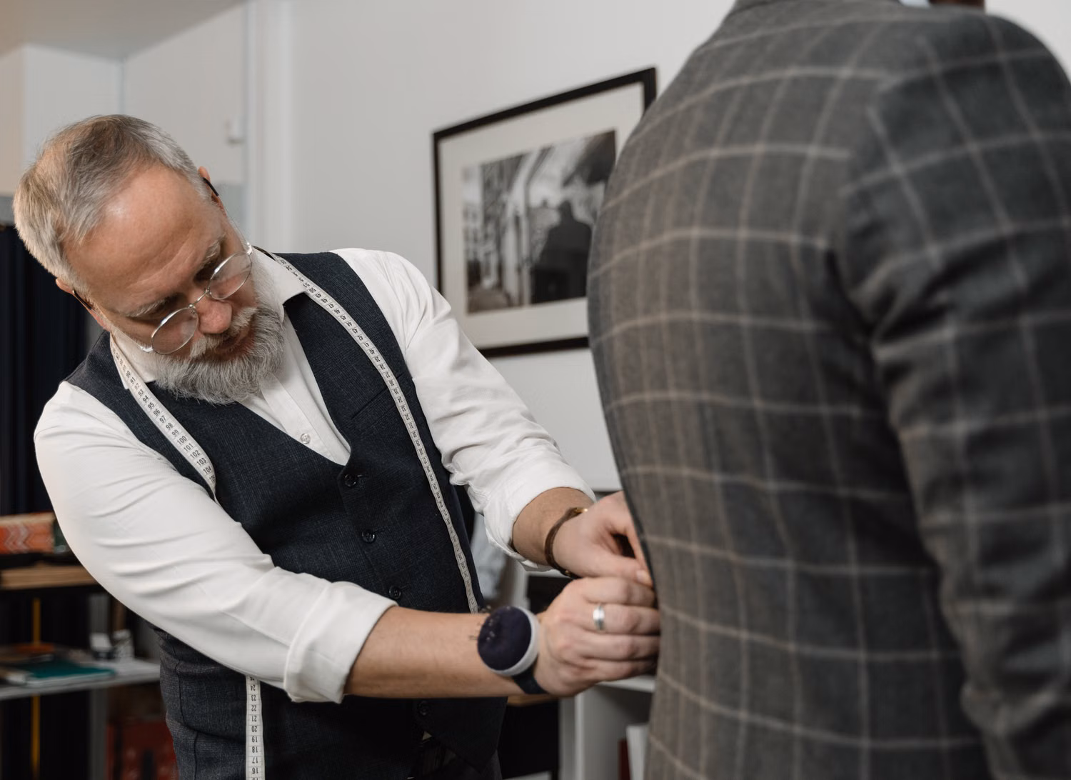 Professional tailor adjusting a man's suit jacket during a fitting